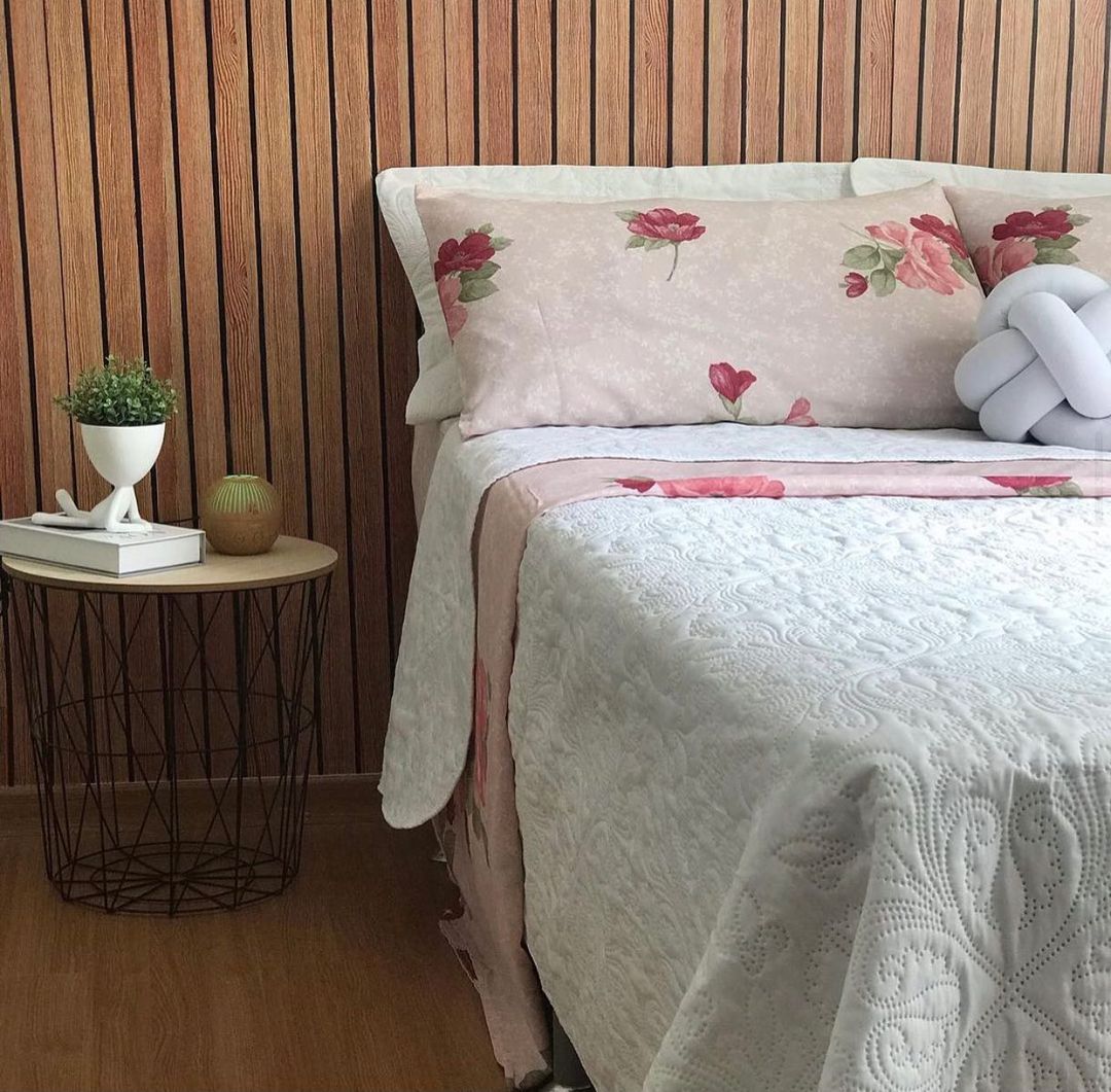 Um quarto de casal, com roupa de cama alegre e uma cabeceira de madeira ripada feita com papel de parede Defacile.